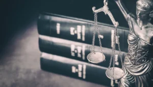 Soška váhy spravodlivosti a súdne knihy na stole, titulný obrázok online šifrovacej hry Reportér v brlohu.