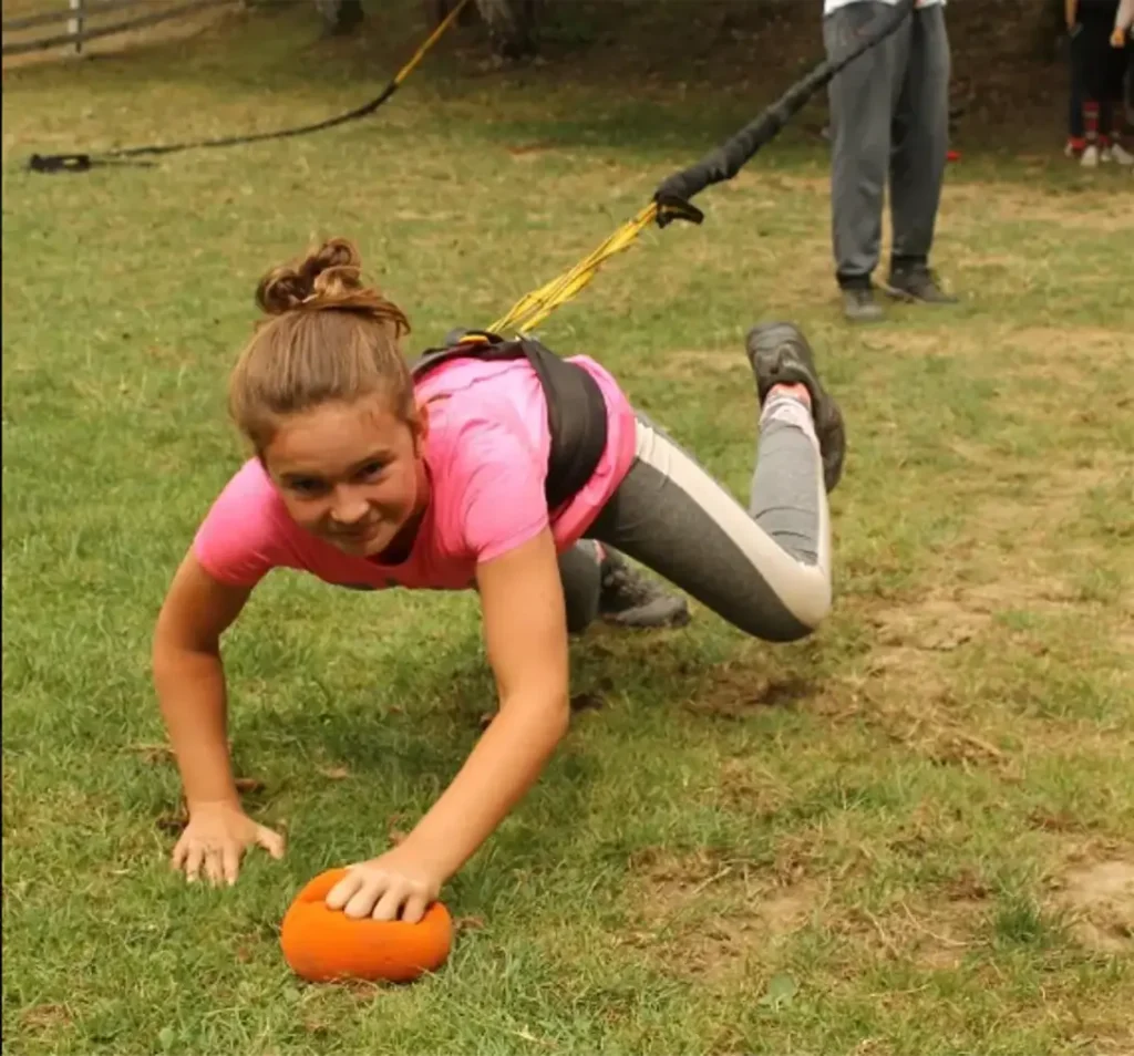 Účastníčka teambuildingu beží v bungee rune proti odporu lana a snaží sa dosiahnuť cieľ